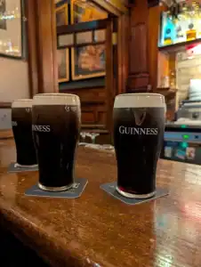 Guinness stout pints on a bar counter, showcasing iconic Irish dark beer in a pub environment.