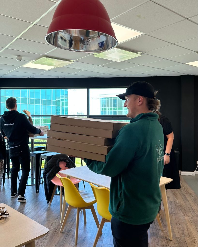 Two team members holding pizza boxes to celebrate Company of the Month