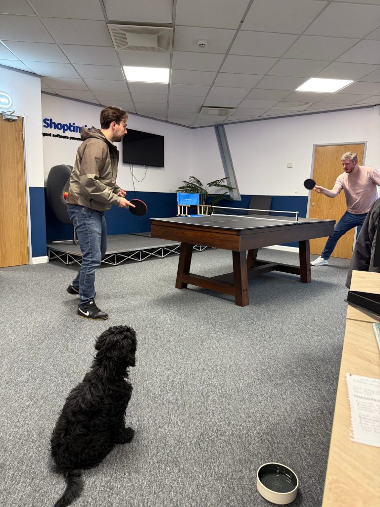 Team members playing table tennis in the Shoptimised office