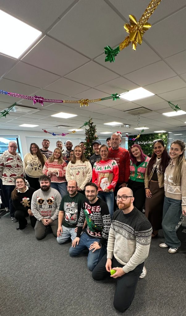 Shoptimised team wearing festive Christmas jumpers in the office