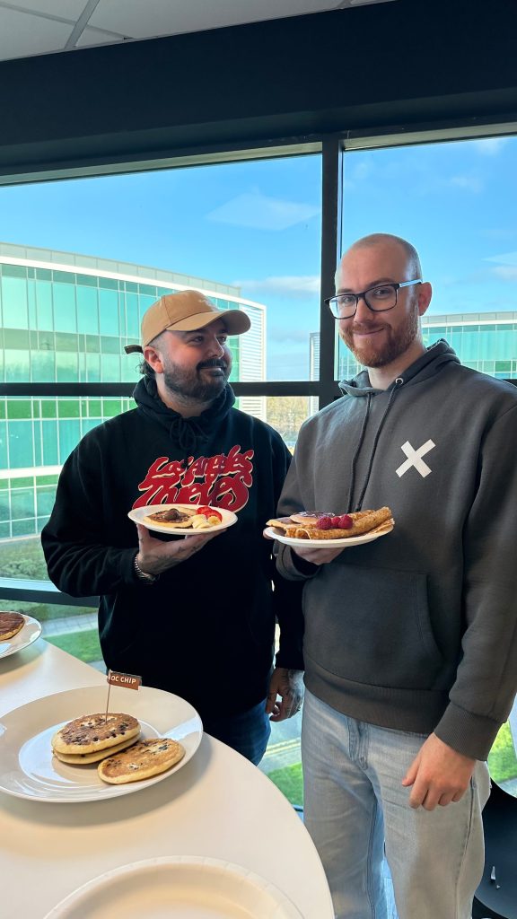 Shoptimised colleagues flipping pancakes on Pancake Day in the office