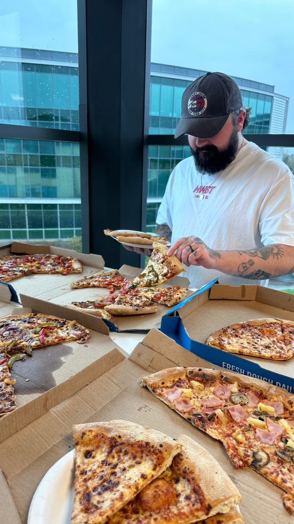 Team sharing pizza during a lunch break at the Shoptimised office